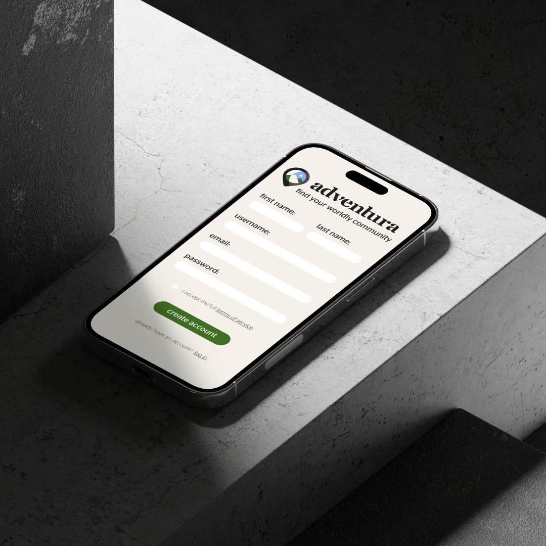 iPhone mockup of Adventura App login against a concrete background.